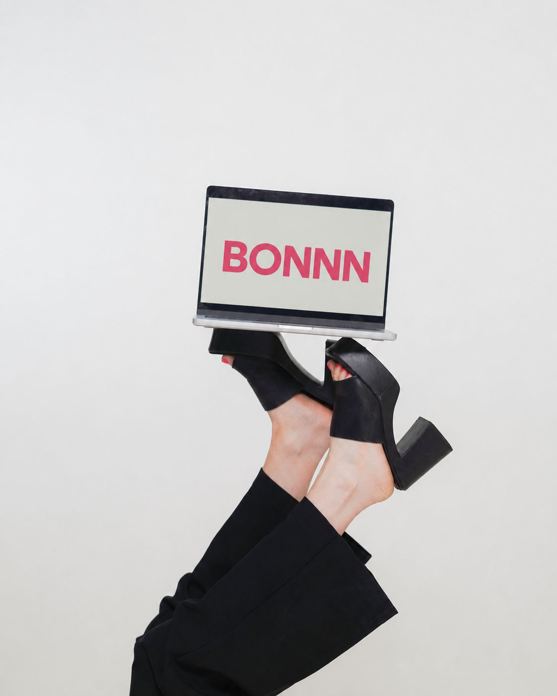 A laptop screen showing the Bonnn logo, held up playfully